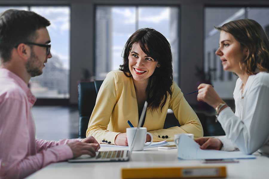 Three people having meeting at a table discussing project