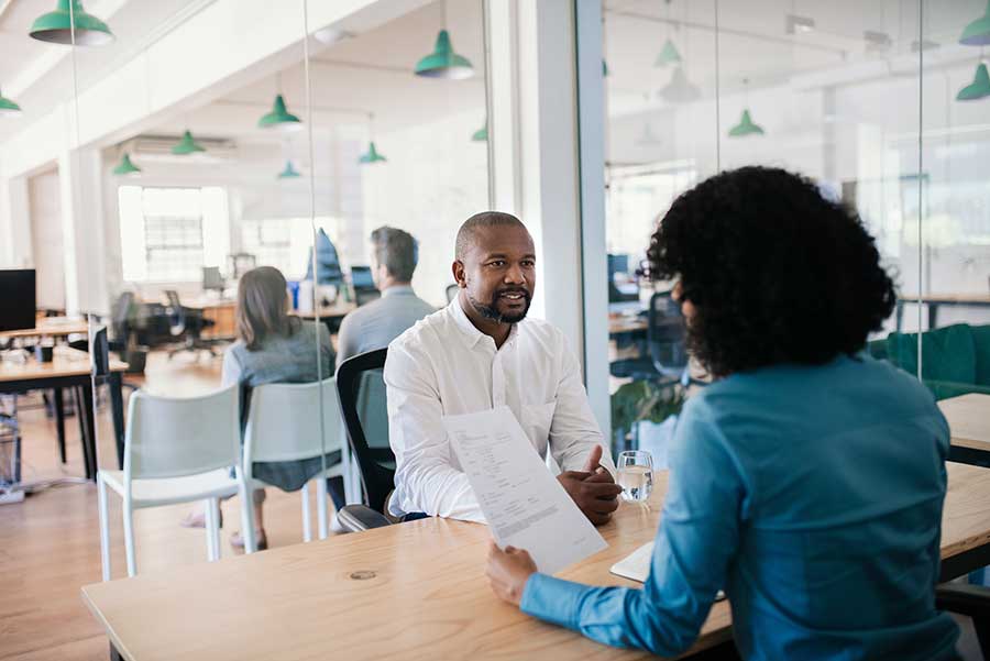 Woman reading paperwork to man in office