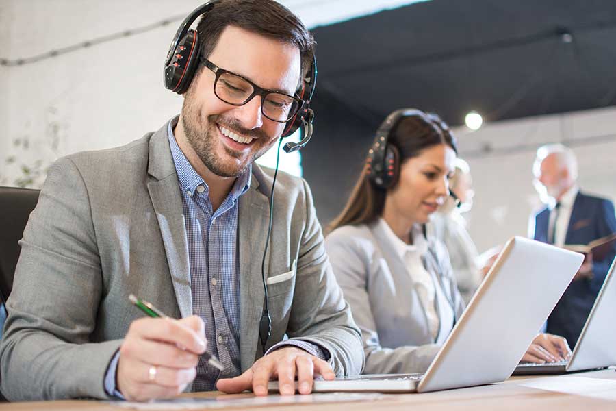 Homme au bureau transcrivant un fichier audio avec des écouteurs