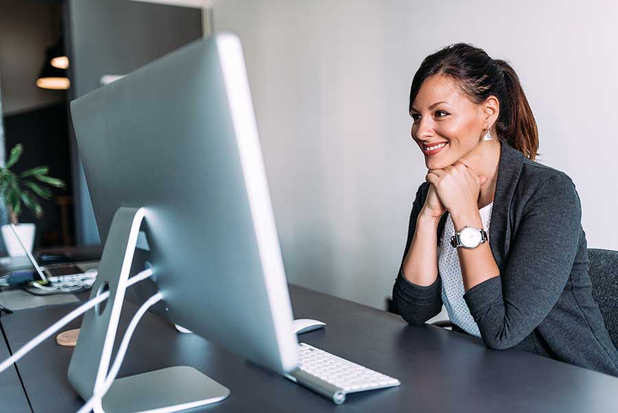 Femme heureuse lisant des sous-titres à l’écran au bureau