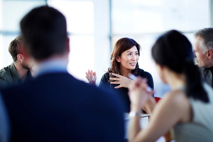 Chinese people talking at meeting with hands gesturing