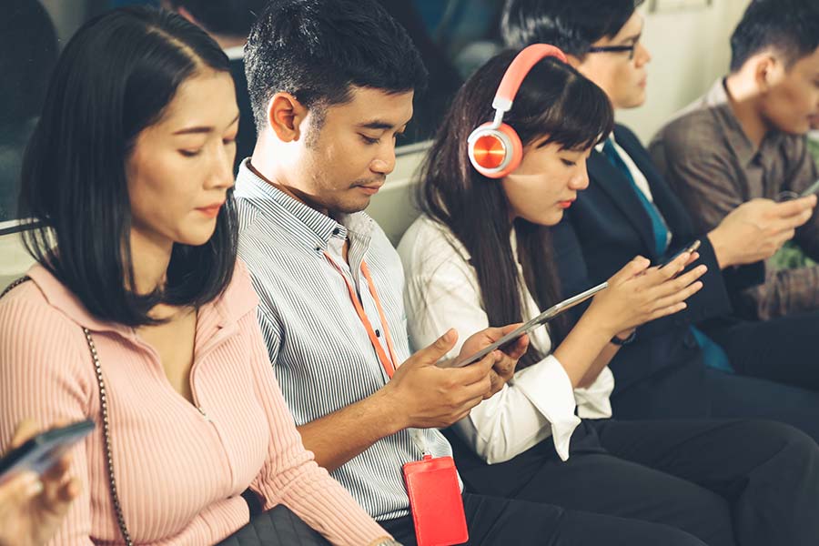 Chinese people commuting on train looking at their devices