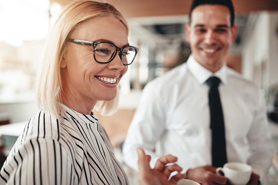 Smiling woman in business meeting having coffee with a man in the background. 