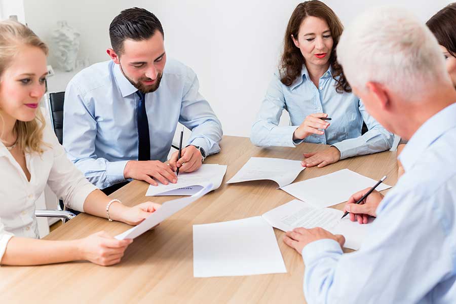 Professionnels d'affaires réunis autour d'une table, en réunion, accompagnés d'un interprète allemand. 