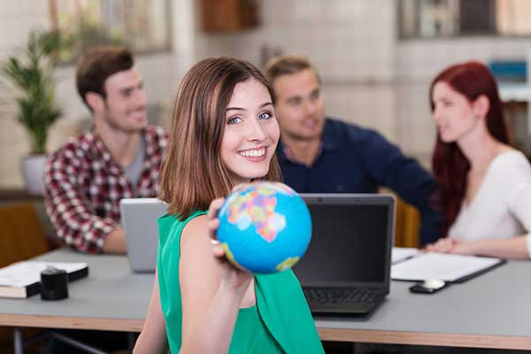 A female multilingual translator holding globe and smiling 