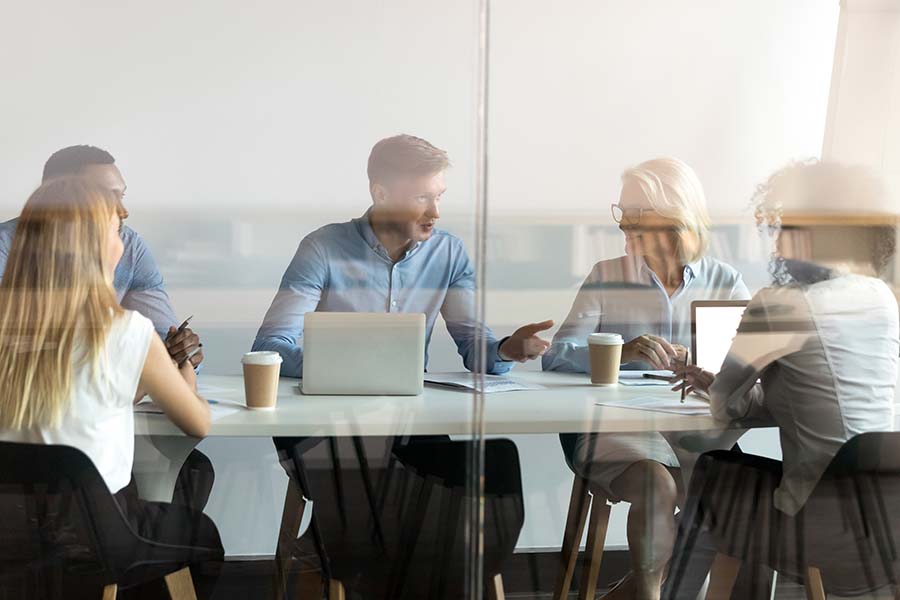 Five people having a meeting at a desk in an office