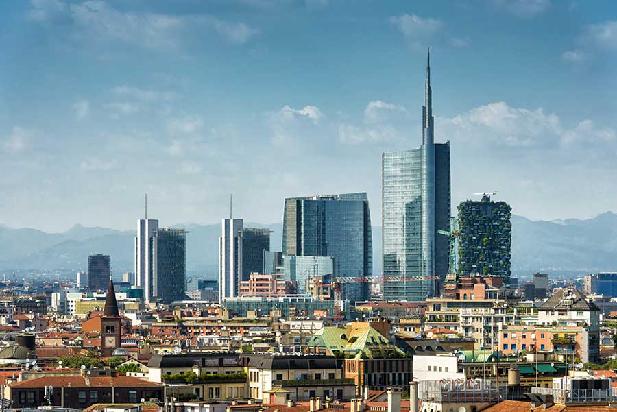 Milan skyscrapers. Blue skies with mountains in the distance.