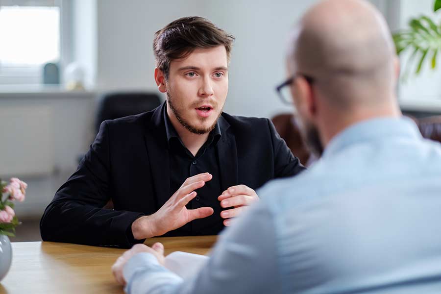 Jeune homme lors d’une rencontre avec un homme plus âgé faisant signe avec ses mains. 