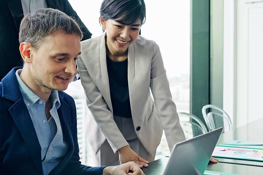 Man and woman looking at a laptop smiling.