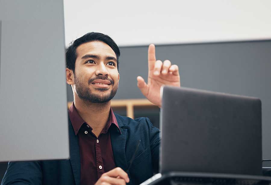 Homme au bureau avec des écrans d’ordinateur pointant. 