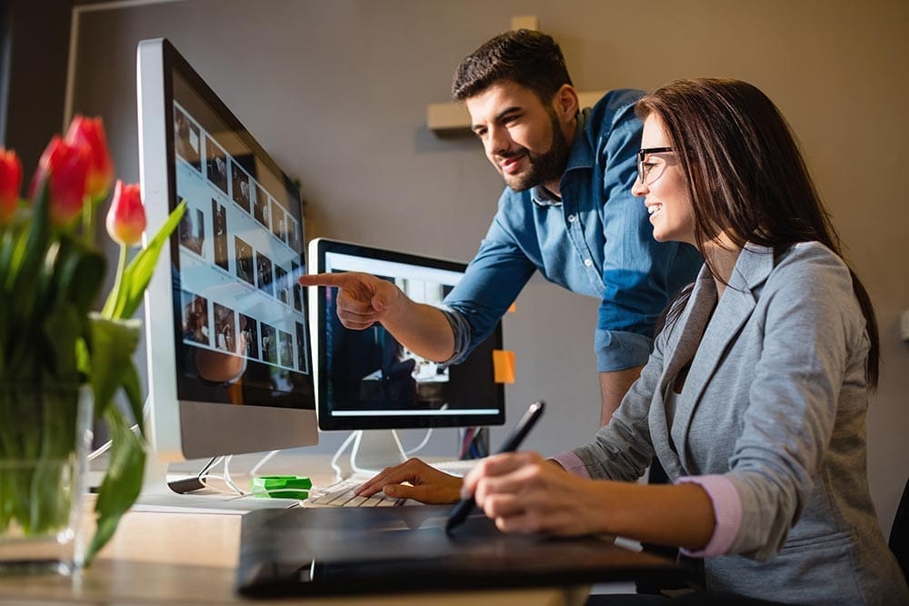 Man and women looking at designs on two screens.